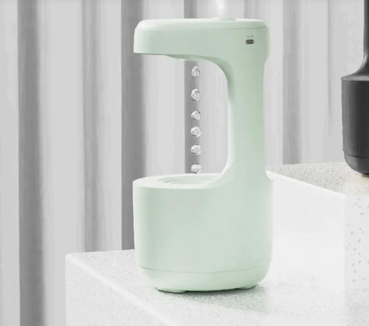 Compact mint green anti-gravity humidifier with floating water drop design on white table