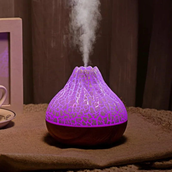 Volcano-shaped humidifier emitting mist with purple ambient light on a brown surface
