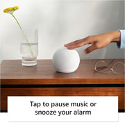 Alaxe Mini Bluetooth Speaker on wooden table with hand tapping to pause music next to a glass vase and eyeglasses