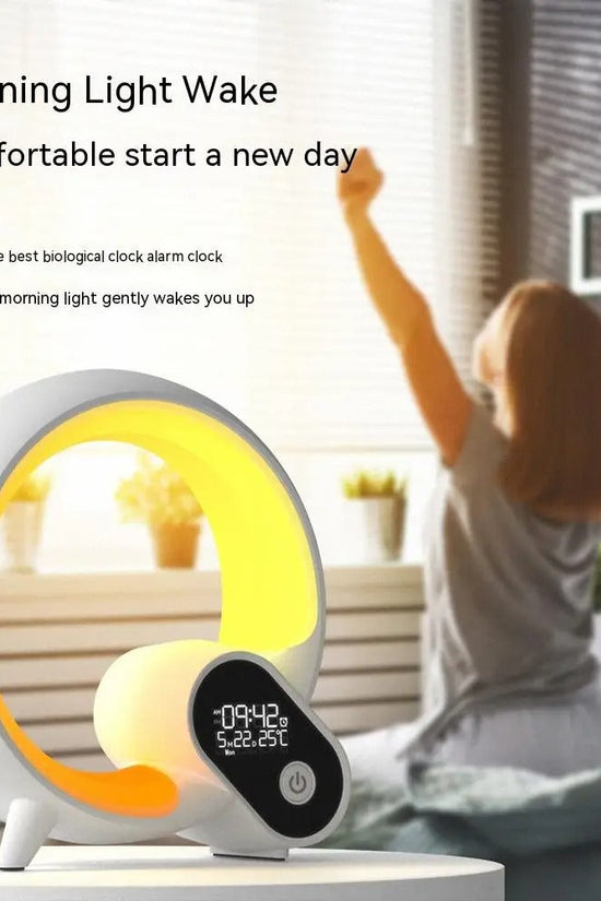 Sunrise alarm clock with gentle wake-up light and Bluetooth speaker on bedside table with woman stretching in background