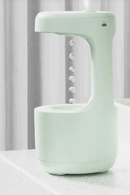 Compact mint green anti-gravity humidifier with floating water drop design on white table